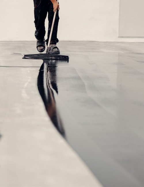 Worker applies grey epoxy resin to a new floor