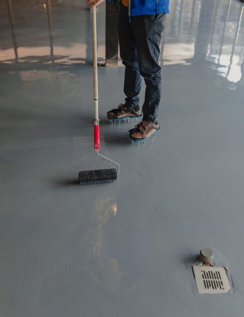 The worker applies gray epoxy resin to the new floor